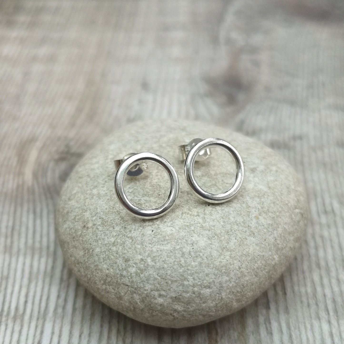 Each earrings is a 10mm wide Sterling Silver open circle attached to silver stud bar.