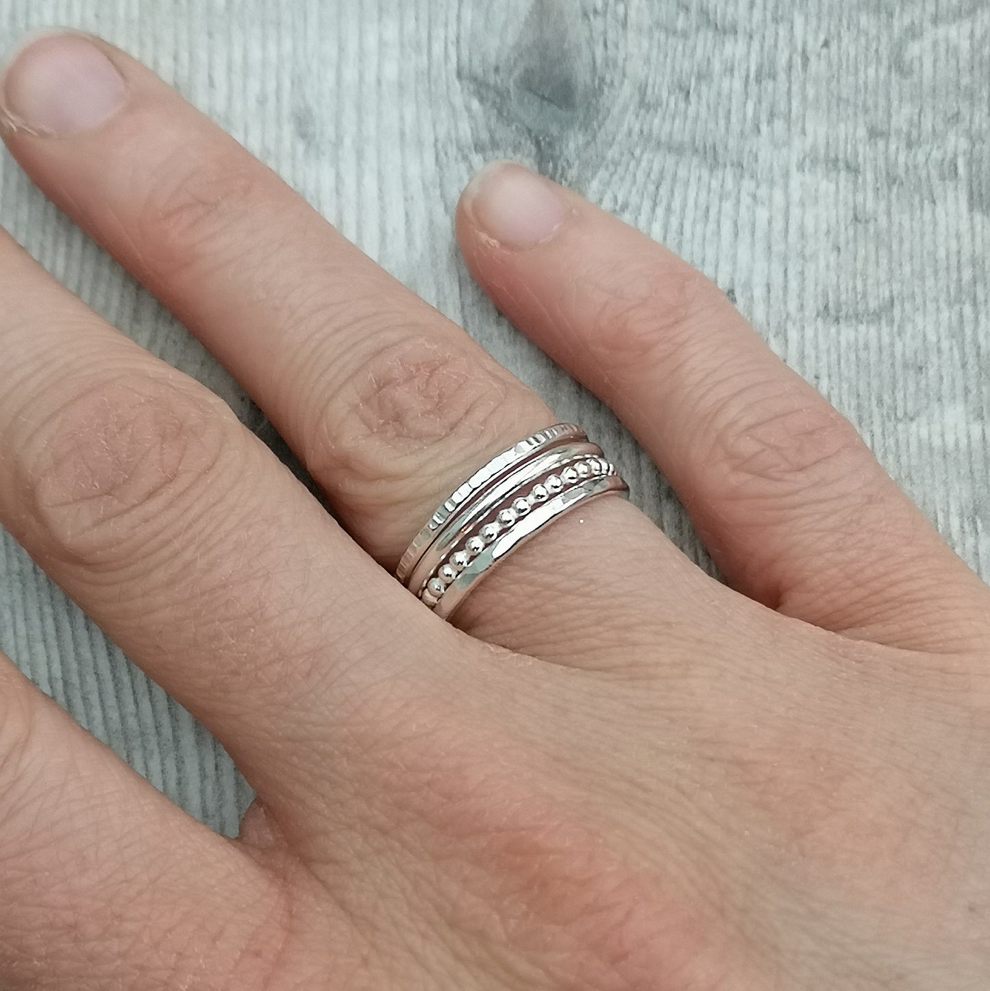 Four separate Sterling Silver rings, one with hammered texture, one beaded texture, one smooth and one lined. For stacking on top of each other, sold separately.