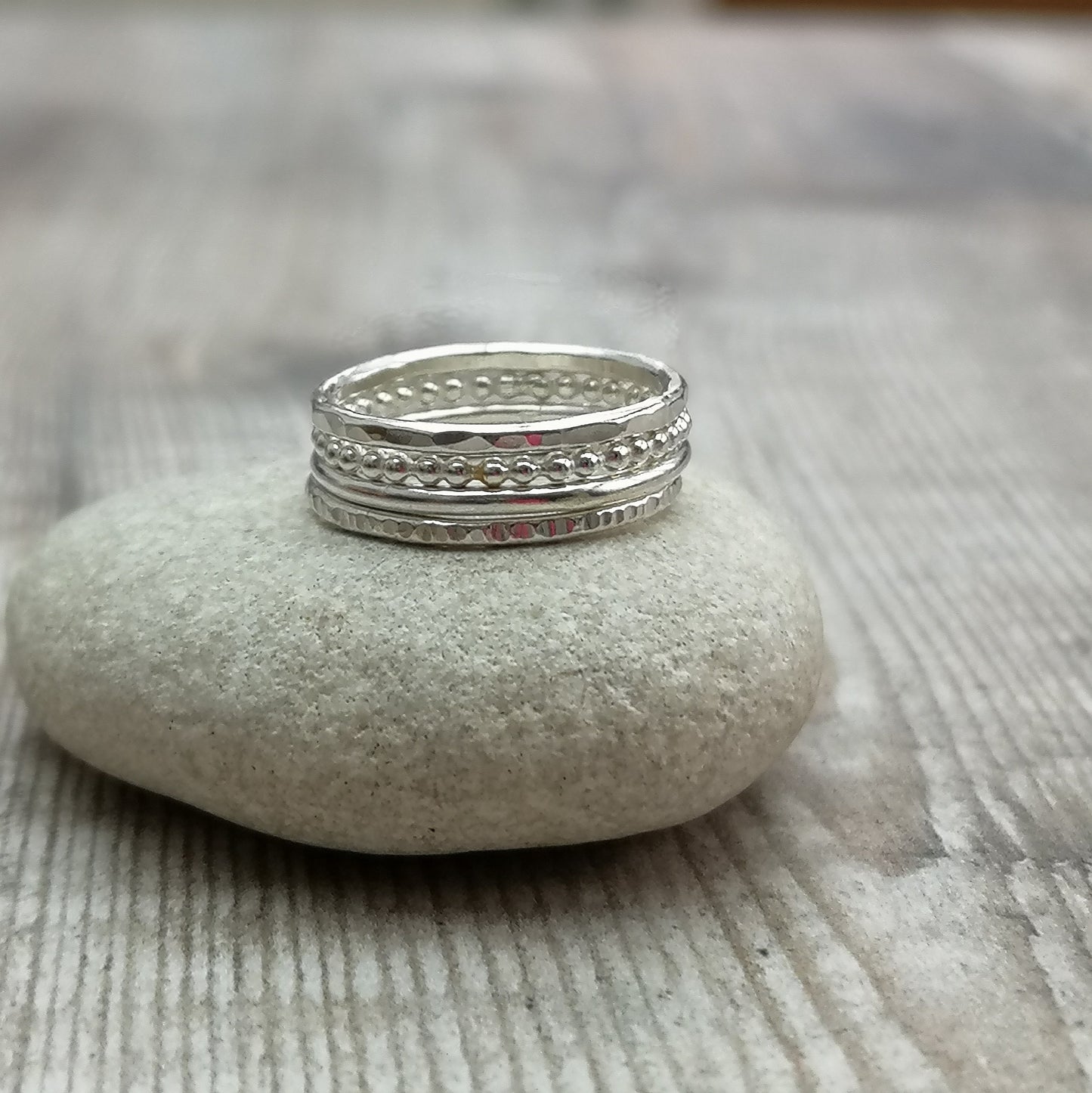 Four separate Sterling Silver rings, one with hammered texture, one beaded texture, one smooth and one lined. For stacking on top of each other, sold separately.