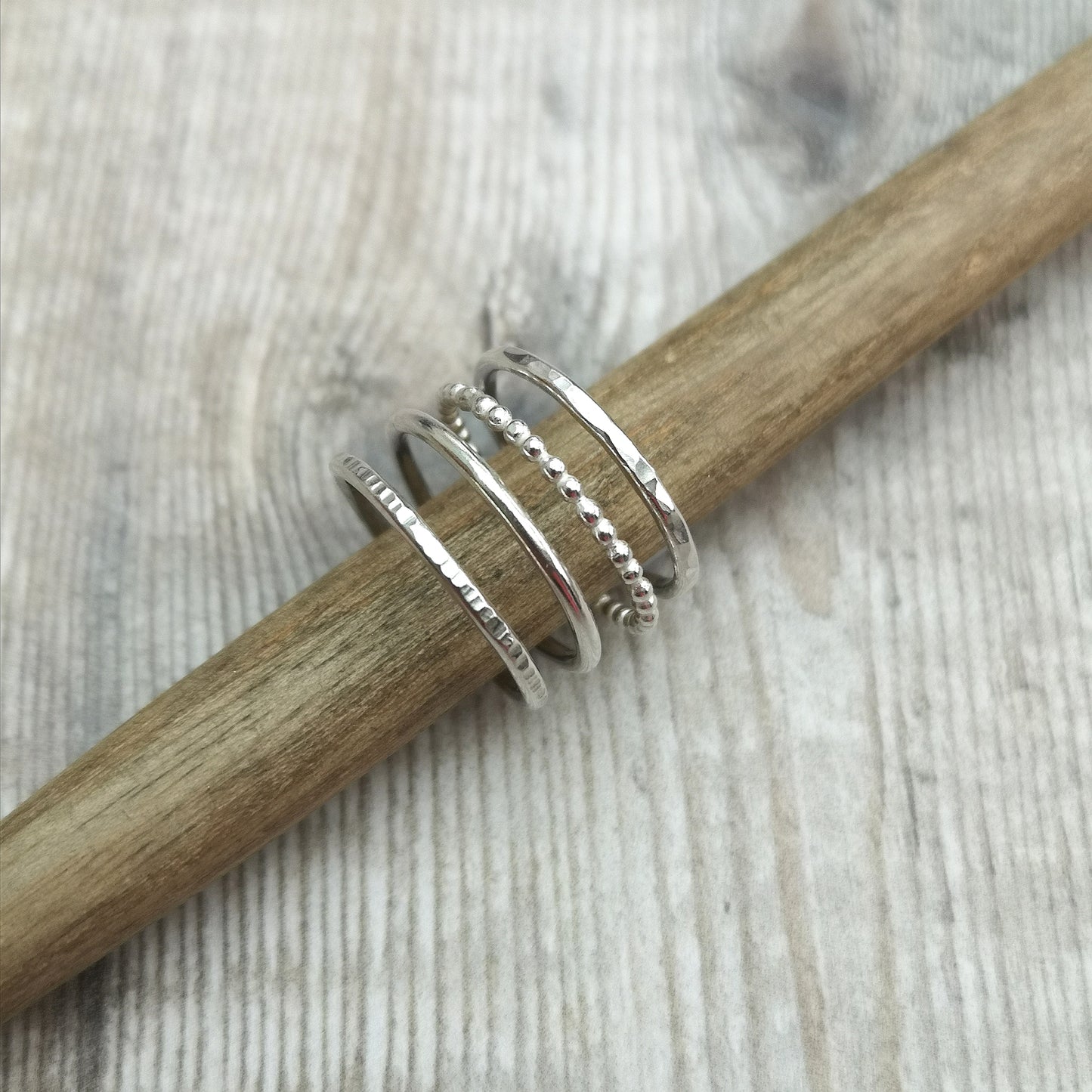 Four separate Sterling Silver rings, one with hammered texture, one beaded texture, one smooth and one lined. For stacking on top of each other, sold separately.