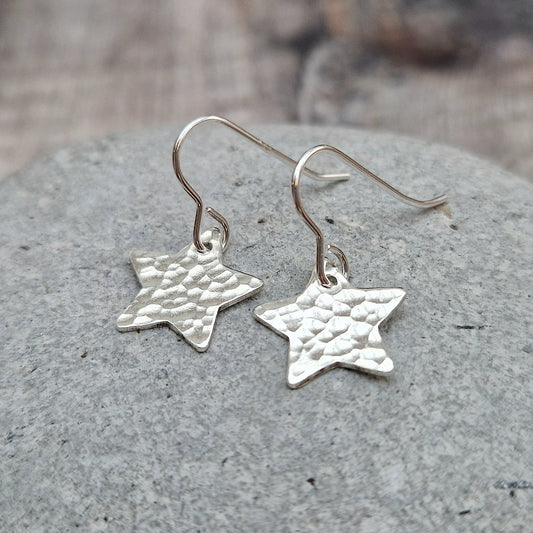 Each earring is a silver star shape with hammered texture finish suspended from silver earring wire.