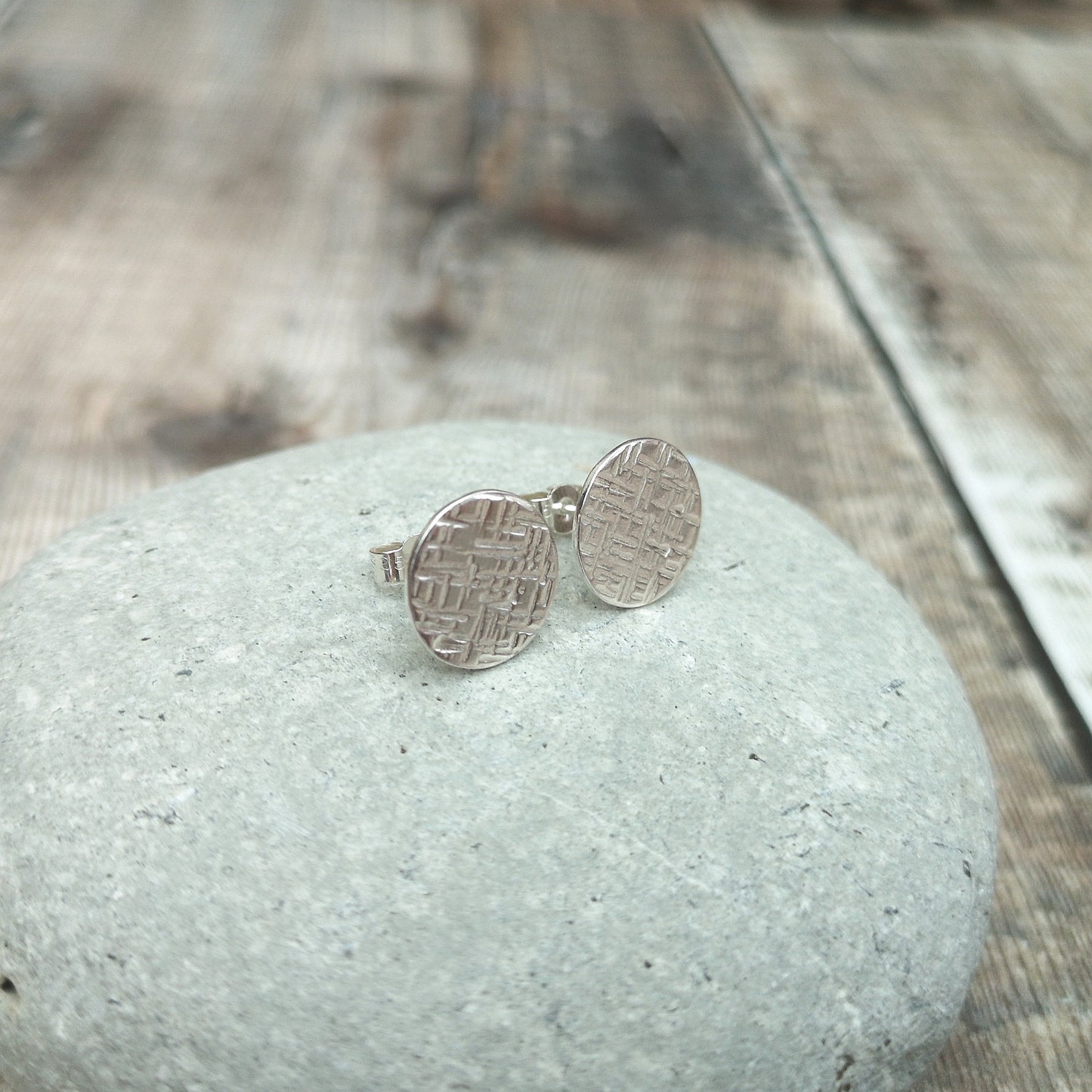 Each earring is a silver round disc stamped with irregular lines and to add a textured finish. Mounted on a silver stud bar.